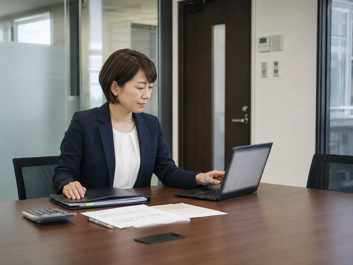 保険相談の面談前に資料とパソコンを準備する担当者(業界イメージ)