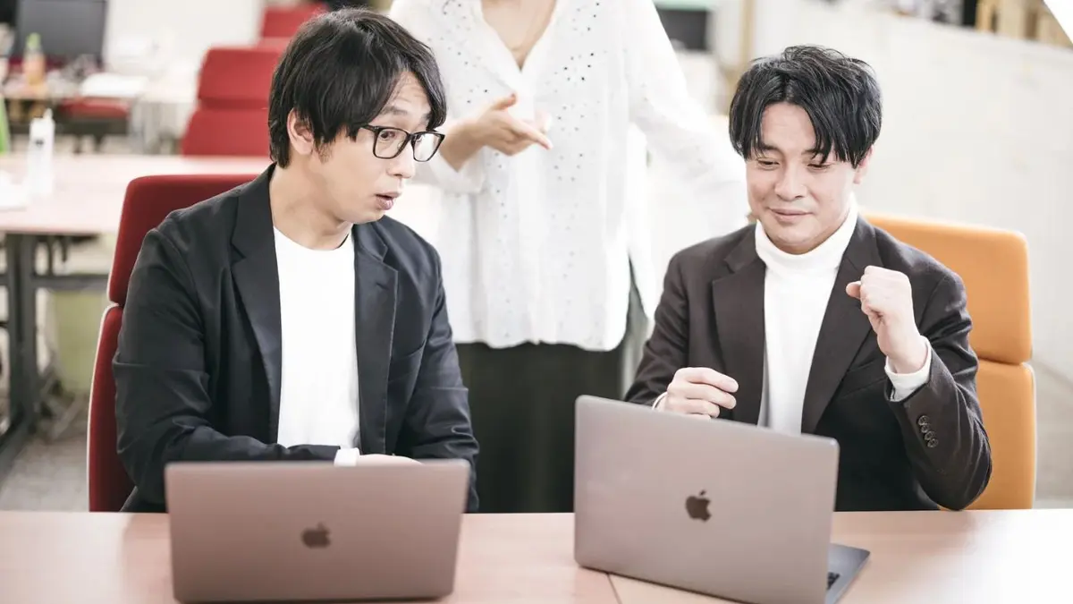 ノートパソコンを囲んで相談する日本人ITチーム（支援業種のイメージ）